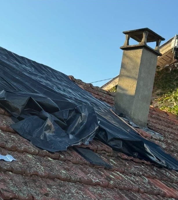 Versant bâché aux tuiles couvertes de lichens autour de la cheminée avant intervention